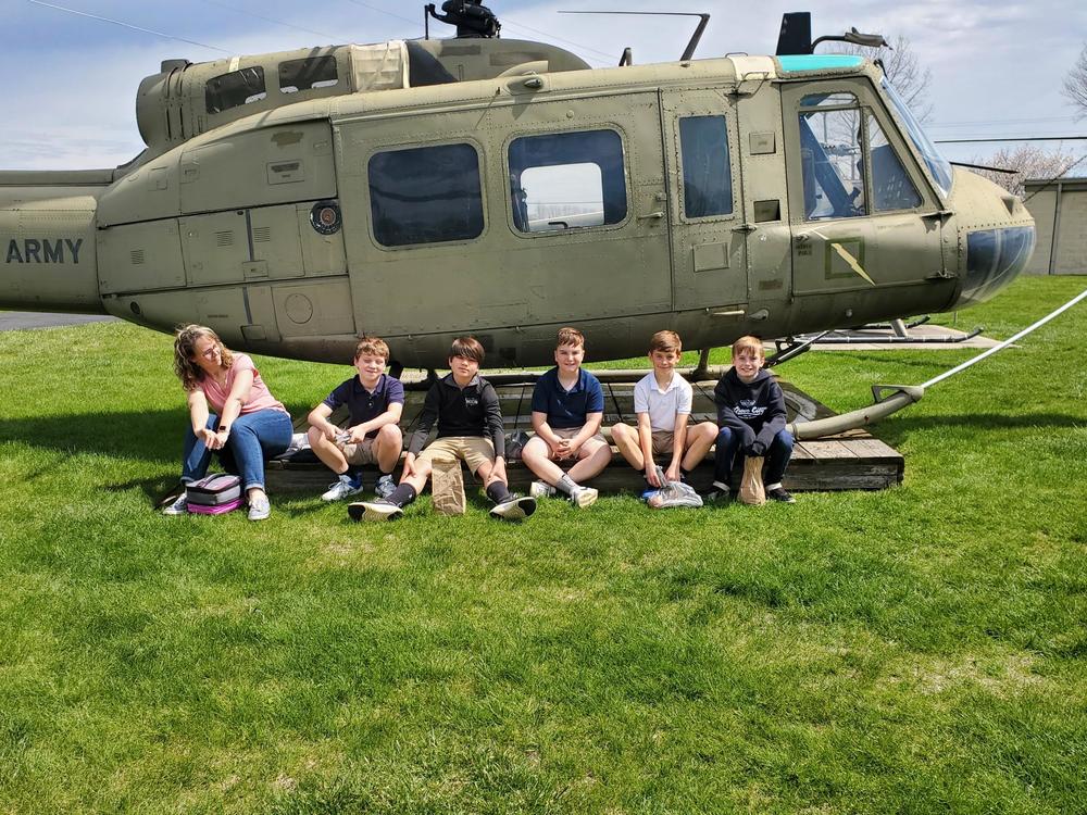 Image of six students sitting in front of helicopter.